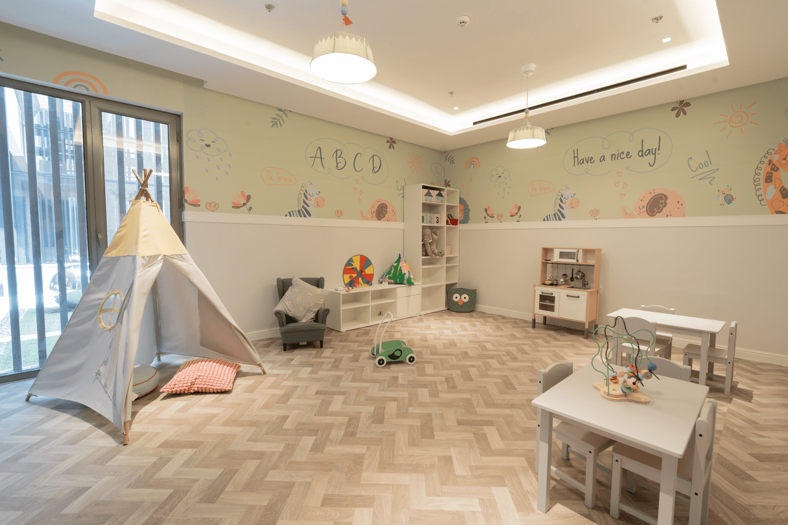 Bright kids' room with small tables, a teepee, and playful wall art.